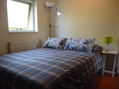 een slaapkamer met een bed met een geruite deken en een raam bij Wellness vakantie villa in Oudemirdum