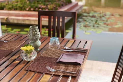 een houten tafel met een tafel voor een maaltijd bij Sukhothai Heritage Resort in Sawankhalok