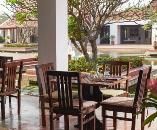 een houten tafel en stoelen op een terras bij Sukhothai Heritage Resort in Sawankhalok