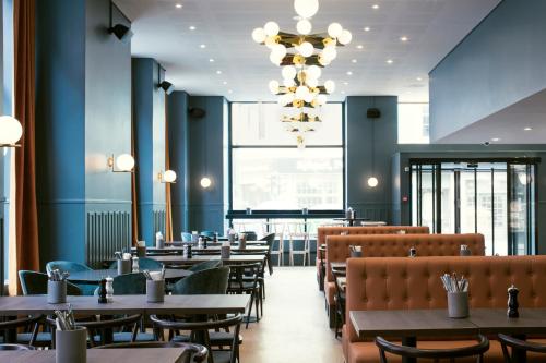 a restaurant with tables and chairs and a chandelier at Hotell Bondeheimen in Oslo