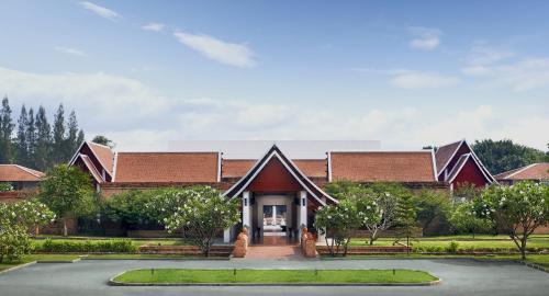 a house with a pathway leading to the front of it at Sukhothai Heritage Resort in Sawankhalok