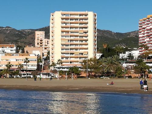 a building on the beach with people walking on the beach at JSM Apartamentos in Benalmádena