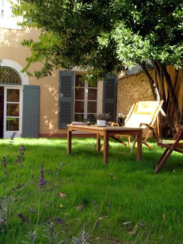 a picnic table and a chair under a tree at Le Couvent in Apt