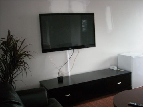 a flat screen tv on a wall in a living room at Grand Motel Saint-Hubert in Longueuil
