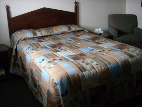 Grand Motel Saint-Hubert في لونغويل: غرفة نوم بسرير وكرسي في غرفة