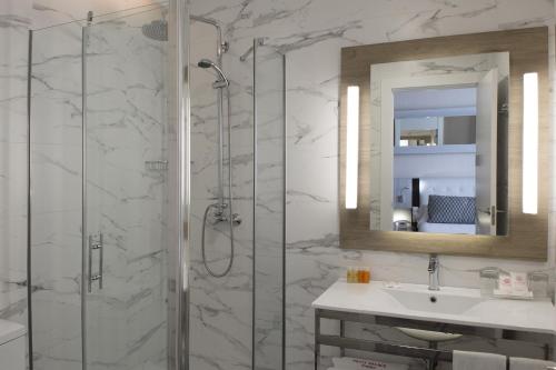 ein Bad mit einer Dusche, einem Waschbecken und einem Spiegel in der Unterkunft Petit Palace Arenal in Madrid
