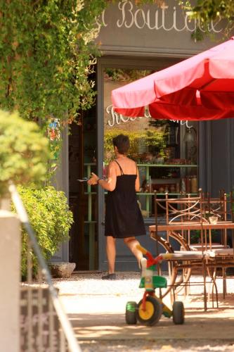 a woman standing in front of a store with a skateboard at Logis Hotel - Restaurant La Marbrerie in Caunes-Minervois
