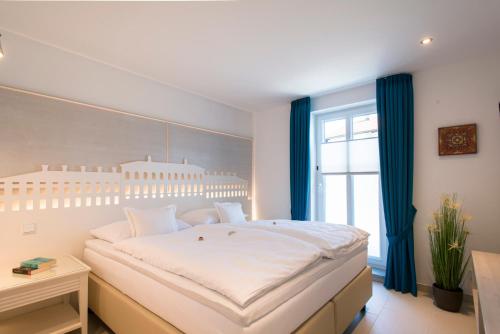 a bedroom with a large white bed with blue curtains at Chiemsee Suiten in Übersee