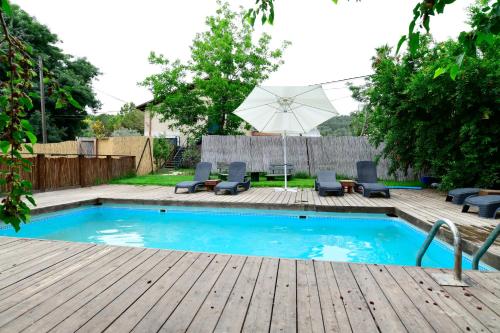 a pool with chairs and an umbrella on a wooden deck at Tzlil Hateva in H̱osen