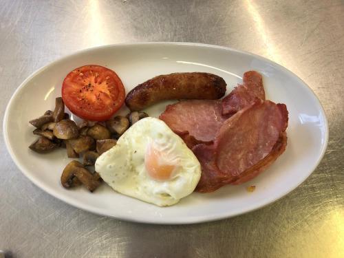 a plate of breakfast food with eggs bacon tomatoes and mushrooms at Yarn Market Hotel in Dunster