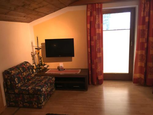 a living room with a tv and a couch and a window at Alpenspirit in Sölden