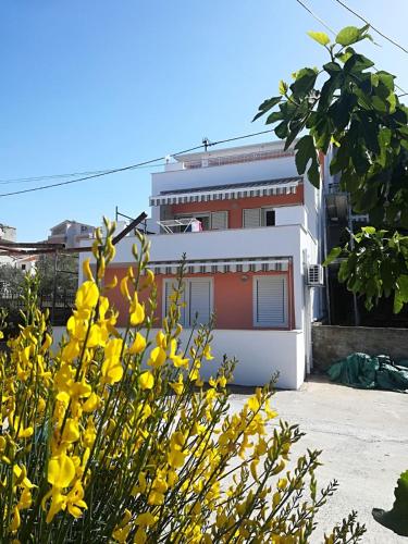 a building with yellow flowers in front of it at Apartment Čiovo Radić in Trogir