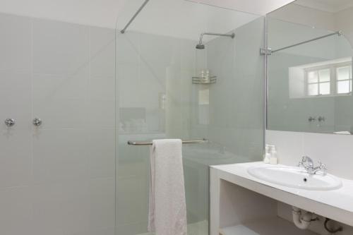 a white bathroom with a sink and a shower at Lemoenfontein in Beaufort West