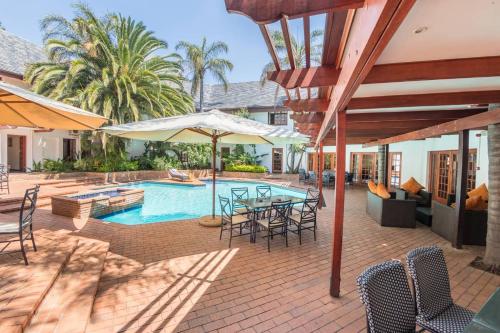 an outdoor patio with a table and chairs and a pool at Constantia Hotel and Conference Centre in Midrand