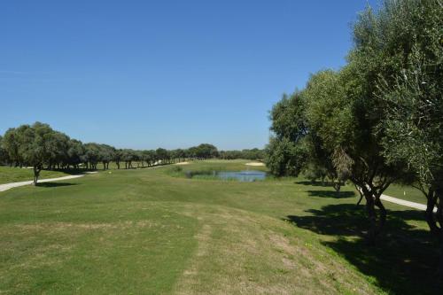 a view of a golf course with a pond and trees at Fairplay Golf & Spa Resort in Benalup Casas Viejas