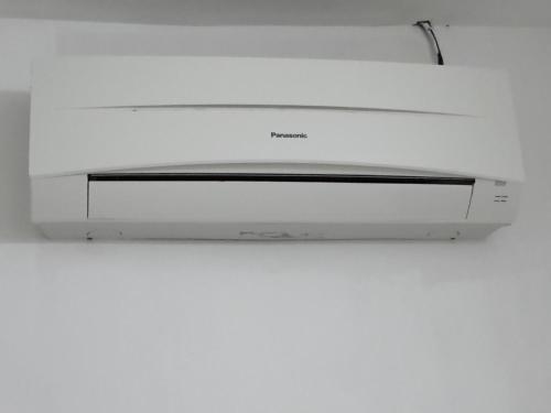 a white microwave oven hanging from a white wall at Rasa Motel in Batu Ferringhi