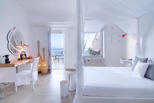 a white bedroom with a white bed and a desk at Santorini Secret Suites & Spa, Small Luxury Hotels of the World in Oia