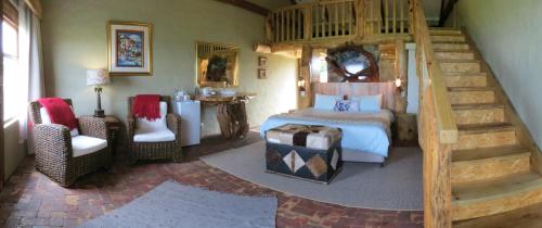 a bedroom with a bed and a staircase in a room at TNiqua Stable Inn in Plettenberg Bay
