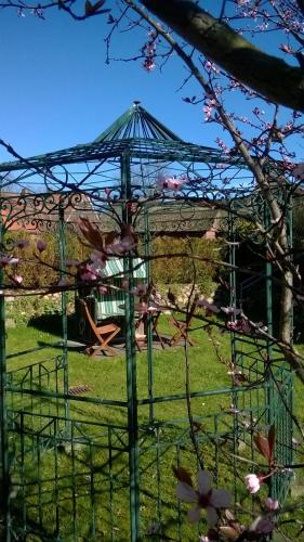 a gazebo in a park with pink flowers at Landhaus Hammoor Stieper Gastronomie GmbH in Hammoor
