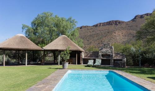 a resort with a swimming pool and two thatched shelters at Lemoenfontein in Beaufort West