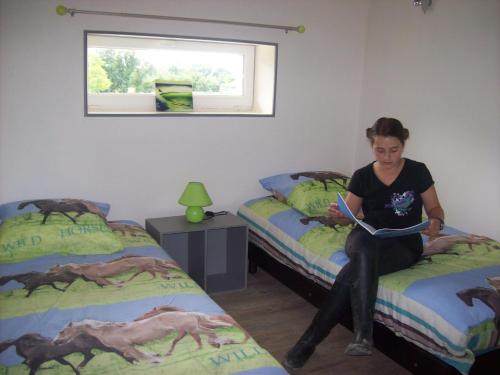 een vrouw op een bed in een kamer met twee bedden bij Gite équestre en Normandie Haras de Sainte Colombe in Sainte-Colombe