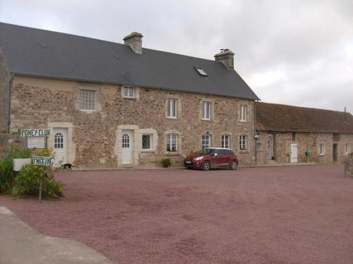 een groot bakstenen gebouw met een auto voor de deur bij Gite équestre en Normandie Haras de Sainte Colombe in Sainte-Colombe
