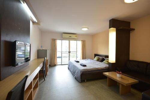 a bedroom with a bed and a tv and a couch at LOFT Salaya in Salaya