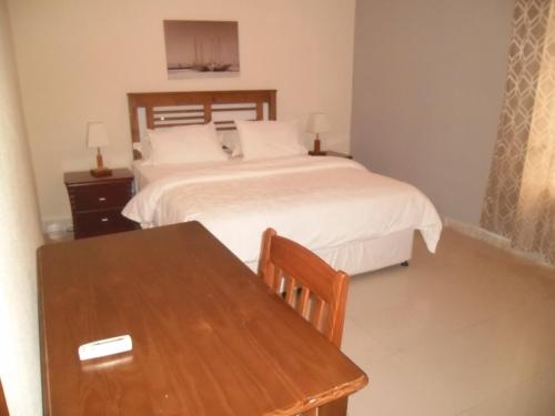 a bedroom with a bed and a wooden table at Hotel Vivi Palace in Matadi