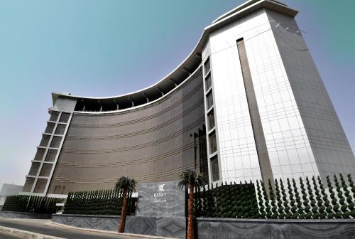 a large building with palm trees in front of it at Bayat Hotel in Khamis Mushayt