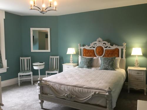 a bedroom with a bed with blue walls and two chairs at Abbey View House in Youghal