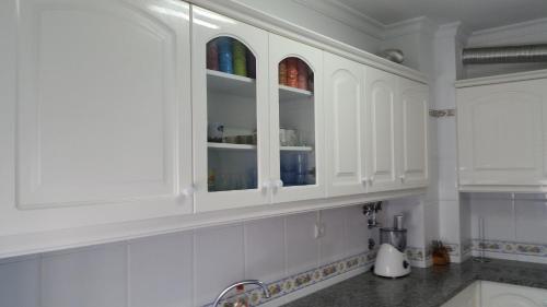 a white kitchen with a sink and white cabinets at Austral Apartment in Quarteira