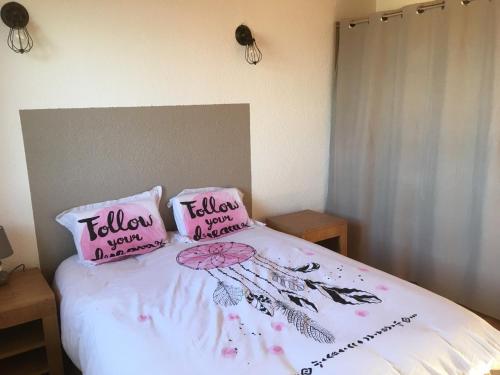 a bed with two pink pillows on top of it at les vignes Ardéchoises - Peuplier in Sarras