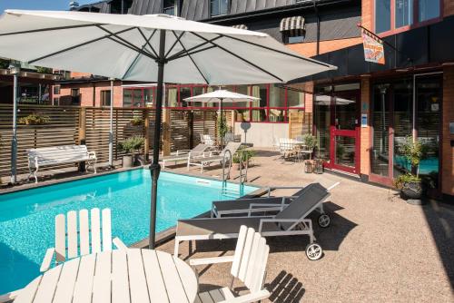 een zwembad met ligstoelen en een parasol en een tafel en stoelen bij Best Western Hotell Hudik in Hudiksvall