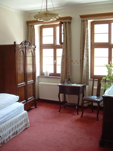 a bedroom with a bed and a desk and windows at Hotel und Gasthof Dreibeiniger Hund in Görlitz