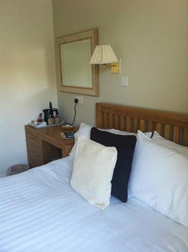 a bedroom with a bed with white sheets and a mirror at Littletown Farm Guest House in Keswick