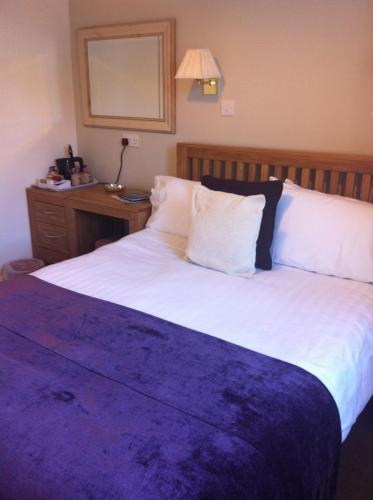 a bedroom with a large bed with a purple blanket at Littletown Farm Guest House in Keswick