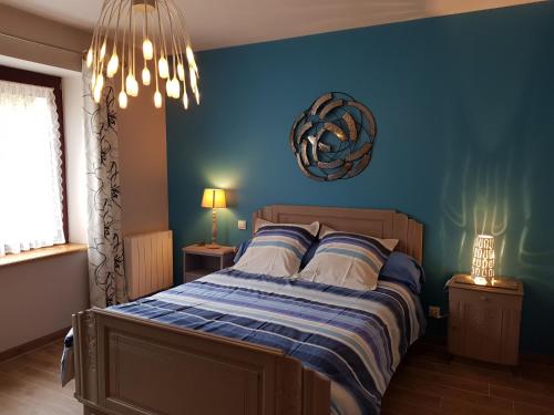 een slaapkamer met een bed met een blauwe muur bij Gîte du Toilier in Thillot-sous-les-Côtes