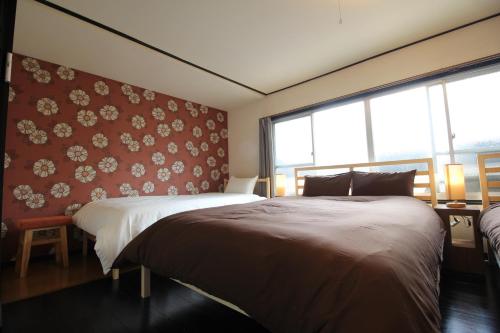 a bedroom with two beds and a red wall at LiB PLUS Kyoto Maiko Han-inn in Kyoto