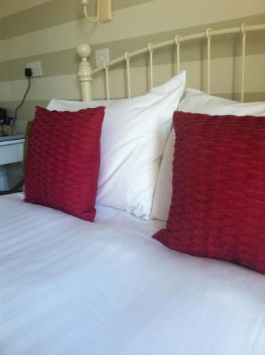 a bed with red and white pillows on it at Littletown Farm Guest House in Keswick