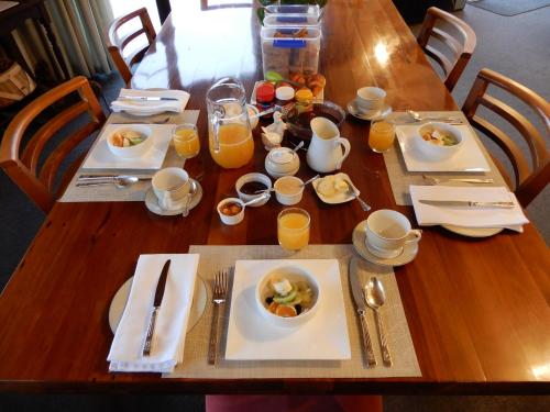 a wooden table topped with plates of food and orange juice at Creel House Bed and Breakfast in Lake Tekapo