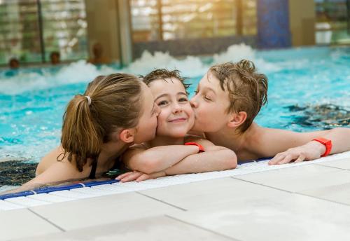 a group of three children laying in a swimming pool at Thermal Hotel Balance Lenti in Lenti
