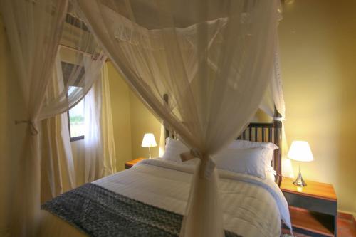 a bedroom with a canopy bed with white curtains at Victoria Forest Resort in Kalangala