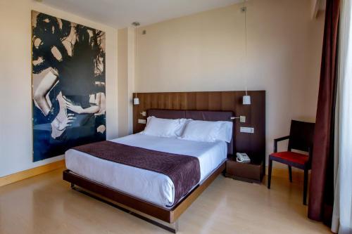 a bedroom with a large bed and a chair at HM Jaime III in Palma de Mallorca