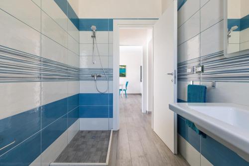 La salle de bains est pourvue d'une douche et de carrelage bleu et blanc. dans l'établissement Villa Evi by BarbarHouse, à Specchiolla