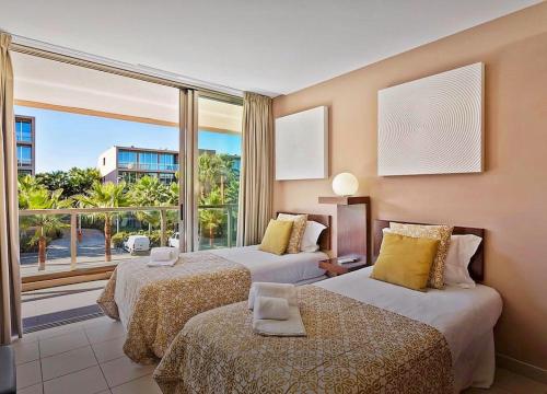アルブフェイラにあるHerdade dos Salgados Beach apartmentのベッド2台と大きな窓が備わるホテルルームです。