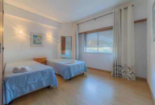クアルテイラにあるTorres Mira Praia by Garveturのベッド2台と窓が備わる客室です。