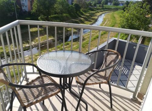 a glass table and two chairs on a balcony at Holiday Wing Apartments in Jagodina