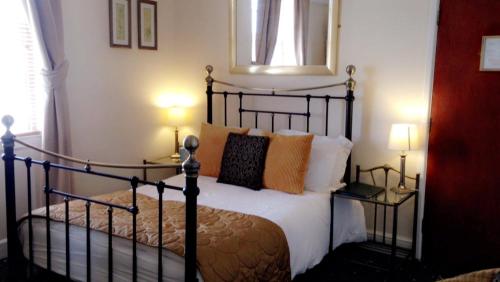 a bedroom with a black bed with pillows on it at The Bay Guest House in Weymouth