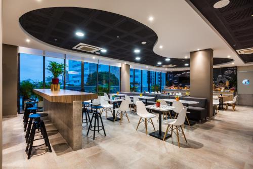 a restaurant with tables and chairs and windows at ibis Barranquilla in Barranquilla