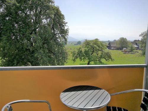 a bench on a balcony with a view of a field at wohnMOTEL - Hinterforst in Altstätten